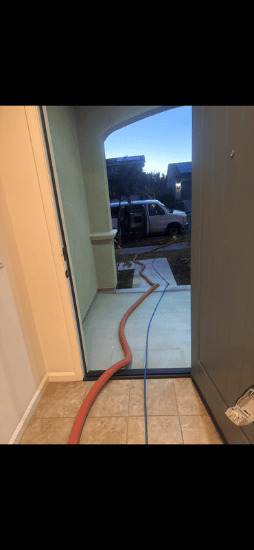 Drainage pipe being installed outside a house, with a view of the street and parked vehicle in the b.